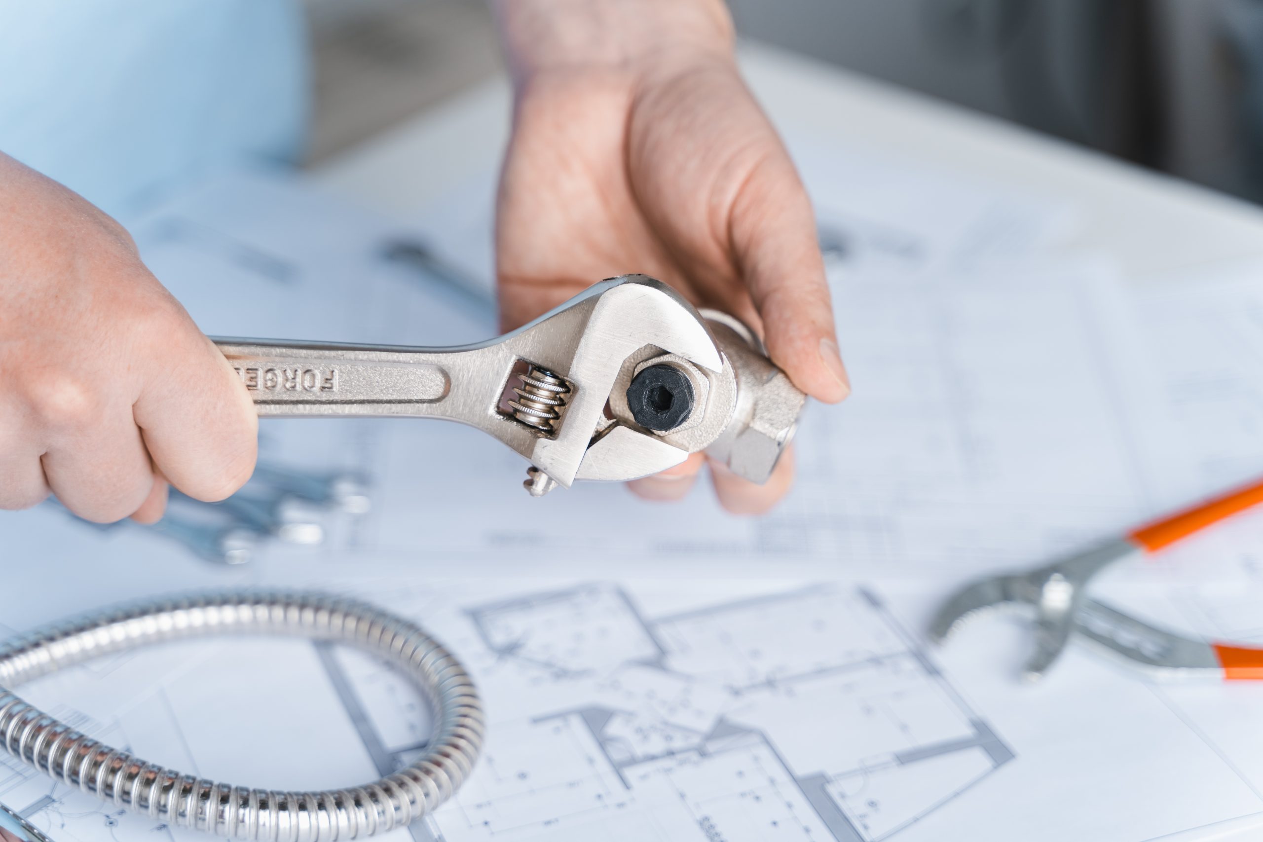 Plumbing project in house.Drawing,diagrams,plan of water supply of apartment,building.Man repairer making repairs at home.Devices,accessories, hose,tap,adjustable wrench,pressure reducer,tape measure.